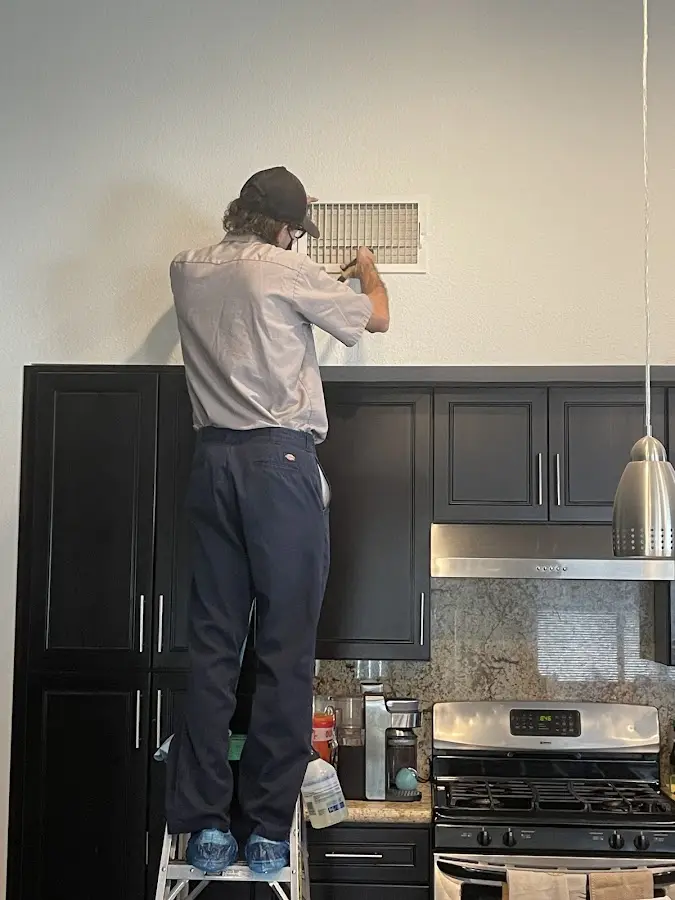 Technician inspecting an air vent during HVAC service in Garden Acres